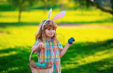 Photo for Bunny boy. Easter bunny children. Kids boy in bunny ears hunting easter eggs in park outdoor - Royalty Free Image