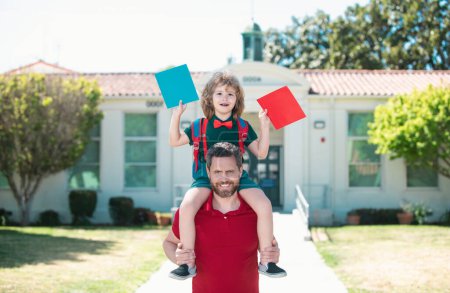 Photo for Father walking son to school. Parent get a son pupil piggyback ride from school. Family lifestyle - Royalty Free Image