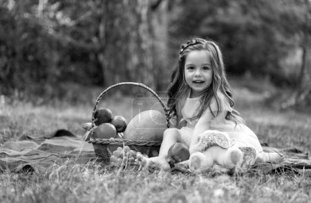 Forest girl on picnic with basket, Kid in sunny park or garden. Little child enjoying leisure