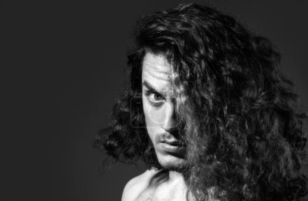 Closeup portrait of male model with long curly hair. Healthcare and hair care concept