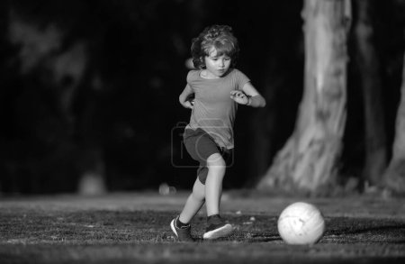 Photo for Boy child kicking football on the sports field during soccer match. Young sporty kids - Royalty Free Image