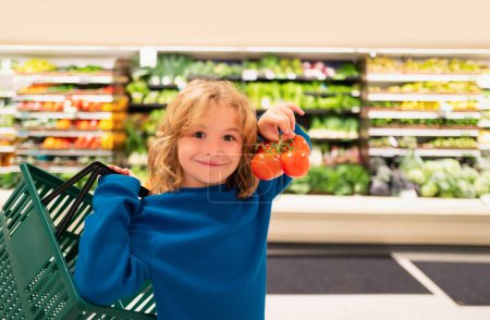 Téléchargez les photos : Enfant avec des tomates fraîches. Shopping au supermarché. Les enfants achètent des courses au supermarché. Le petit garçon achète des légumes frais à l'épicerie. enfant acheter de la nourriture - en image libre de droit