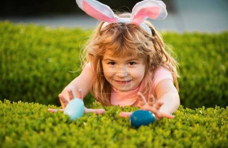 Photo for Kids boy hunting easter eggs. Children celebrating easter. Kid in rabbit costume with bunny ears outdoor - Royalty Free Image