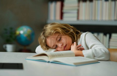 Foto de Niño de escuela cansado, alumno aburrido durmiendo en la escuela. Educación para niños y concepto escolar. Retrato del alumno escolar durmiendo en el libro en la biblioteca - Imagen libre de derechos