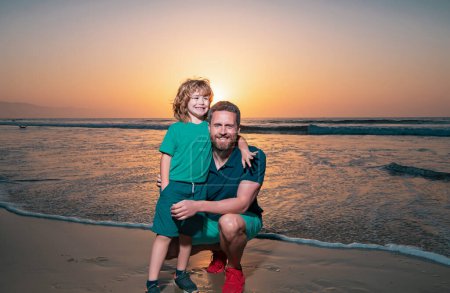 Téléchargez les photos : Père et fils s'embrassent sur la plage au coucher du soleil - en image libre de droit