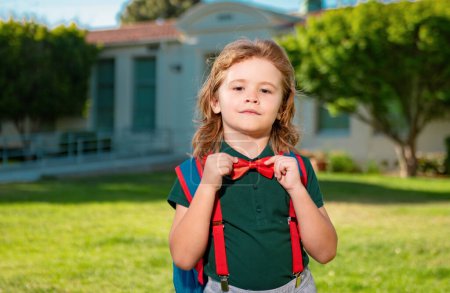 Téléchargez les photos : Portrait de l'élève avec sac à dos près de l'école en plein air - en image libre de droit