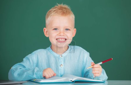 Photo for Kid writing in notebook in class. Little student child studying in classroom at elementary school. Education and kids knowledge concept - Royalty Free Image