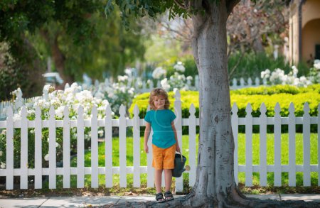 Téléchargez les photos : Enfant actif garçon arrosant des plantes sur le jardin. Concept d'activité d'apprentissage de la culture végétale pour les écoliers. Éducation des enfants de la nature - en image libre de droit