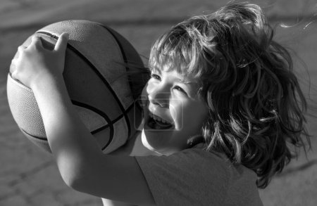 Téléchargez les photos : Mignon sourire excité garçon joue au basket-ball. Enfant drôle visage gros plan - en image libre de droit