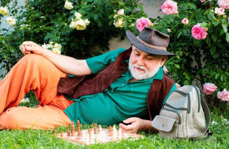 Photo for Spring senior leisure concept. Old man in spring garden with chess. Hobby. Happy old age - Royalty Free Image