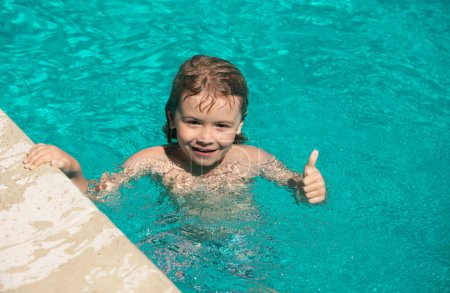 Photo for Child boy with thumbs up swim in swimming pool - Royalty Free Image