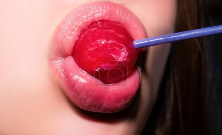 Photo for Sucking lips. Closeup female lips with pink lipgloss holding in mouth red lollipop candy. Lollipop on a face - Royalty Free Image