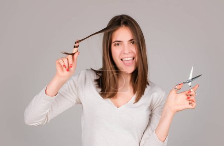 Foto de Mujer con tijeras con corte de pelo. Chica divertida con pelo liso con tijera profesional. Concepto de cuidado del cabello - Imagen libre de derechos