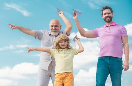 Foto de Tres generaciones de hombres juntos, retrato de un hijo sonriente, padre y abuelo con un avión de juguete. Niño jugando con avión y soñando futuro - Imagen libre de derechos