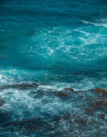 Photo for Cooled black lava beaten by the Atlantic ocean waves. View of sea waves hitting rocks on the beach. Waves and rocks - Royalty Free Image