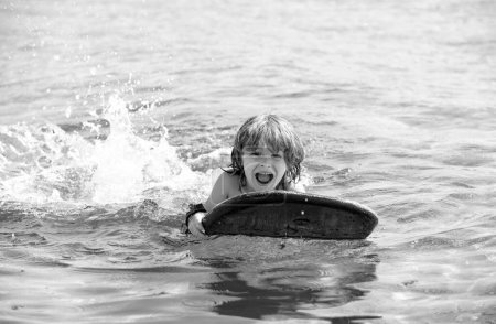 Foto de Vacaciones de verano. Niño con tabla de surf. Verano. Sonriente niño nadando - Imagen libre de derechos