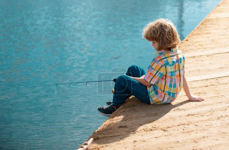 Kinderangeln an Fluss oder See. Jungfischer. Freizeitaktivitäten im Sommer. Kleiner Junge angelt mit Rute am Fluss