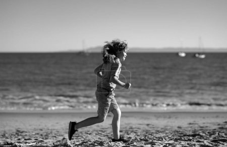Foto de Un chico corriendo en la playa. Niño feliz correr en el mar en vacaciones de verano - Imagen libre de derechos