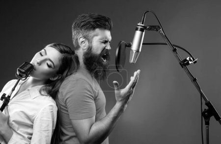 Téléchargez les photos : Couple chantant. Couple en studio d'enregistrement. Performance musicale vocale. Chanteur chantant chanson avec un microphone - en image libre de droit