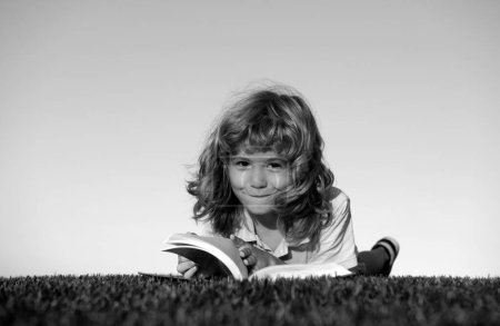 Photo for Kids imagination, dreaming children. Cute kid reading book on green grass - Royalty Free Image