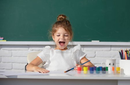 Foto de Niña linda pintura infantil con pinturas de color y pincel. Escuela de pintura lección, dibujo arte - Imagen libre de derechos