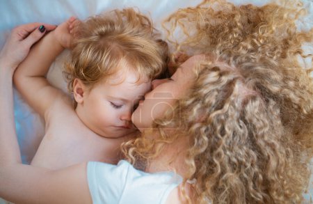 Téléchargez les photos : Une jeune mère et un bébé couchent ensemble. Doux rêves et sommeil des enfants - en image libre de droit