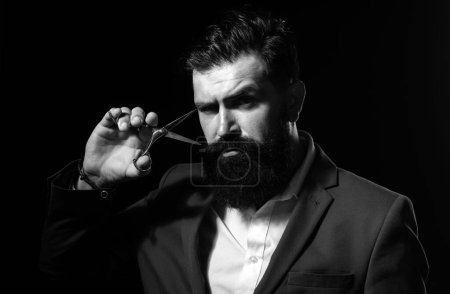 Bearded man, portrait of man with long beard and moustache. Barber scissors for barber shop. Vintage barbershop, shaving. Brutal serious male with modern hairstyle on black