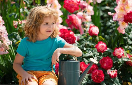 Foto de Lindo niño regando flores en el jardín en el día de verano. Niño usando regadera en el día de verano. Pequeño ayudante - Imagen libre de derechos