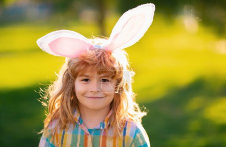 Téléchargez les photos : Petit lapin visage de garçon. Enfant garçon dans les oreilles de lapin en plein air. Enfant ayant Pâques dans le parc - en image libre de droit