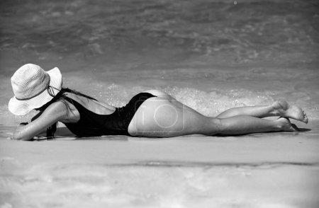 Photo for Girl near sea. Summer sunbath. Vacation on beach. Woman in black swimwear lying on sandbeach - Royalty Free Image