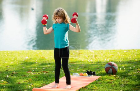 Photo for Fitness child. Children having workout. Sport kids activities outdoor. Child raising a dumbbell - Royalty Free Image