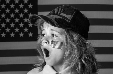 Téléchargez les photos : Kid célébration indépendance jour 4 juillet. Concept des États-Unis d'Amérique. Enfant avec drapeau américain. Jour du Souvenir. Visage drôle d'enfants avec drapeau américain sur la joue. Visage surprenant des enfants - en image libre de droit