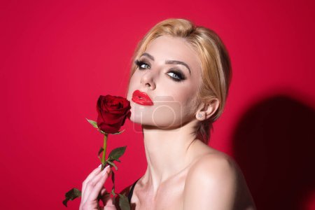Téléchargez les photos : Portrait d'une jolie charmante fille rêveuse tenant des roses rouges, isolée sur fond de studio rouge - en image libre de droit