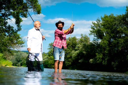 Foto de Hombre mayor maduro con amigo pescando. Vacaciones de verano. Gente feliz y alegre. Hombres barbudos capturando peces. Pescador con caña de pescar. Actividad y hobby - Imagen libre de derechos