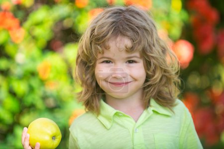 Téléchargez les photos : Enfant mignon garçon mangeant une pomme à l'extérieur. Amusement extérieur pour les enfants. Une alimentation saine - en image libre de droit