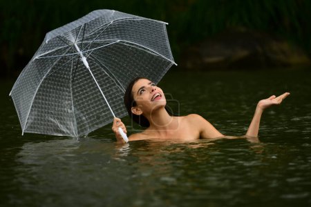 Sexy topless Woman with umbrella in water. Summer rain. Rainy weather. Rain rain go away. Sexy woman sensually relaxing in water. Recreation wellness and wellbeing. Sensual rain