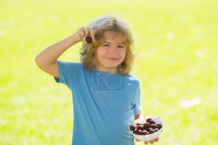 Photo for Funny kid eats cherries. Excited face. Cherry for kids. Teenager child hold plate cherries. Healthy food. Summer child - Royalty Free Image