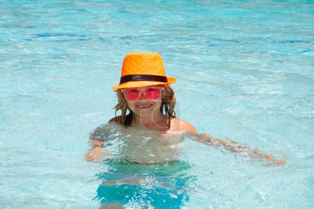 Foto de Kid splashing in swimming pool. Little child boy in swimming pool swim on summer vacation. Beach sea and water fun - Imagen libre de derechos
