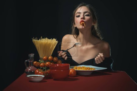 Photo for The woman savors the spaghetti with a sensual touch. She enjoys each bite of the pasta in a sensual manner. Food sensual experience. Italian food meal sensual satisfaction - Royalty Free Image
