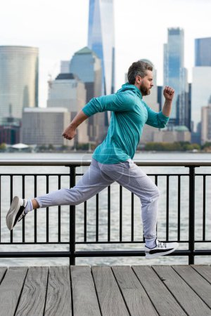 Téléchargez les photos : Cours ! Un homme en bonne santé qui court à New York. Sport de fitness, homme coureur fait du jogging près de Manhattan. Un homme courant dans la rue américaine. Un homme en tenue de sport à New York. Vêtements de sport pour coureurs matures - en image libre de droit