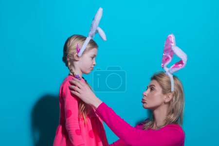 Foto de Feliz Pascua. Una madre y su hija pintando huevos de Pascua. Familia feliz preparándose para la Pascua. Linda niña pequeña con orejas de conejo en el día de Pascua - Imagen libre de derechos