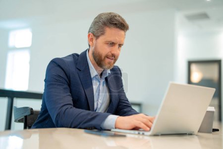 Photo for Businessman with laptop at office. Businessman in suit in office work on laptop computer. Office business man using laptop. Businessman work on laptop. Businessman have online work in office interior - Royalty Free Image