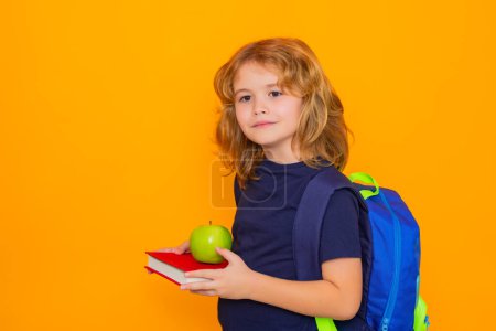 Téléchargez les photos : Je retourne à l'école. Enfant de l'école primaire avec livre et pomme isolé sur fond jaune. Petite étudiante, intelligente élève nerd prête à étudier. Connaissance, éducation et apprentissage - en image libre de droit