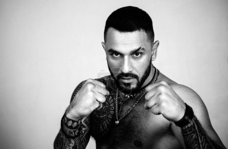 Sport, fighting concept. Brutal tattooed man ready for a battle. Strong fighter cropped portrait. Gray background. Copy space for advertising. MMA