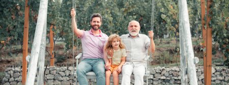 Banner of Fathers day. Father and son with grandfather swinging on the swing in the park outdoor, family relationship grandfather and grandson