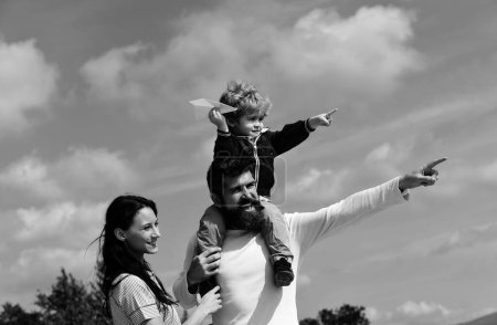 Foto de Feliz familia padre e hijo en el prado con una cometa en el verano en la naturaleza. Disfrutar. Familia feliz hijo jugando con avión de papel. Generación. Paternidad - Imagen libre de derechos