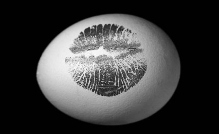 Foto de Impresión de labio rojo en huevo de Pascua sobre fondo negro. Impresión de labios rojos en huevo blanco. Caza de huevos - Imagen libre de derechos