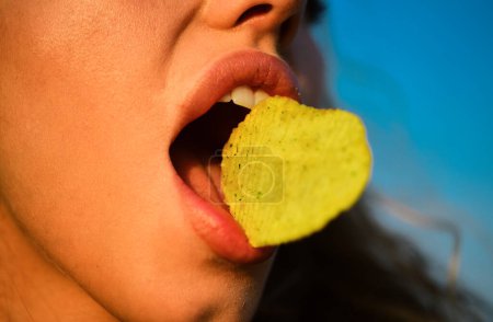 Foto de La boca femenina come papas fritas. Patatas fritas con dientes, lengua y labios se cierran. Sabrosa comida rápida deliciosa. Comiendo patatas fritas. Comida rápida - Imagen libre de derechos