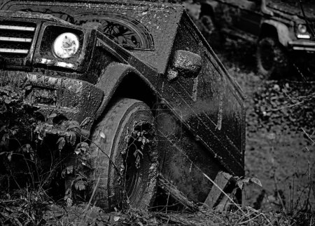 Bottom view to big offroad car wheel on country road and mountains backdrop. Offroad vehicle coming out of a mud hole hazard. Drag racing car burns rubber. Extreme. Tires in preparation for race