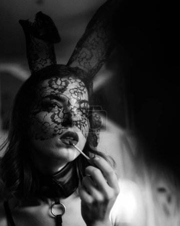 Photo for Sexy woman with bunny ears colors lips with red lipstick. Bunny rabbit easter concept. Attractive young woman wearing bunny ears - Royalty Free Image